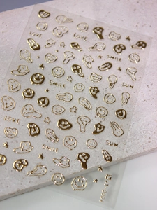 Macro detail of gold metallic smile stickers on grey stone for nail art and DIY decoration
