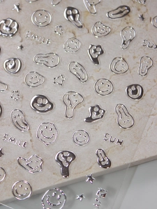 Macro shot of silver 3D melting smiley faces and stars metallic nail art stickers
