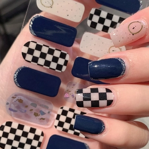 Navy blue and checkerboard nail stickers with gold accents for a DIY manicure look