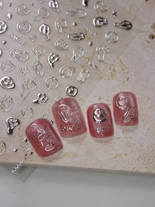 Macro view of 3D silver melting smiley nail stickers applied on pink cat-eye manicure