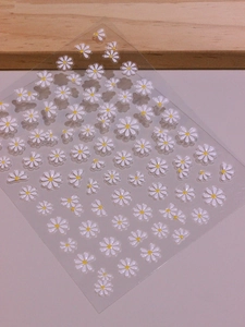 Detail of 5D white daisy nail art stickers with 3D texture on transparent film