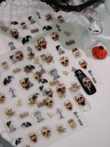Macro detail of 3D Halloween nail decals featuring skull, tombstone and bat patterns