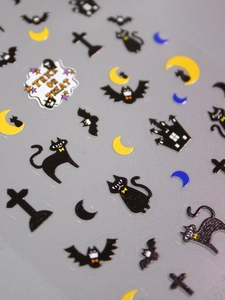 Macro detail of 3D Halloween nail stickers featuring matte black cats, bats and moon patterns
