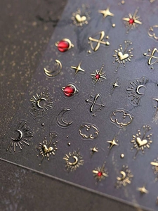 Macro shot of 3D embossed gold and red star moon celestial nail art stickers