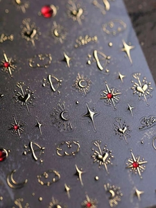 Detail of 3D gold embossed nail stickers with stars moons and red jewel accents