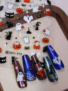 Detail of Halloween nail stickers with ghost and pumpkin patterns on metallic nails