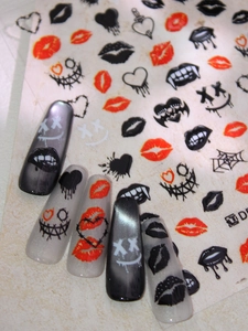 Vue détaillée de stickers ongles lèvres rouges et crânes sur manucure effet œil de chat