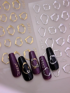 Detailed macro of 3D metallic gold and silver nail art stickers on purple nails