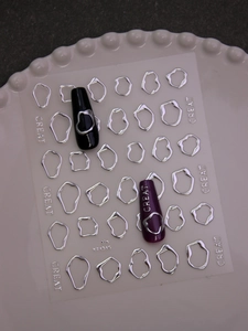 Macro view of 3D silver fluid metal nail stickers with irregular hollow frame designs