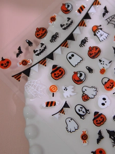 Detail of 3D Halloween nail stickers featuring pumpkins, ghosts and bats on a plate