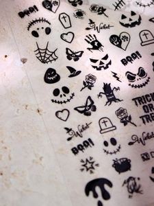 Macro detail of 3D embossed Halloween nail art stickers with black pumpkin and spider patterns