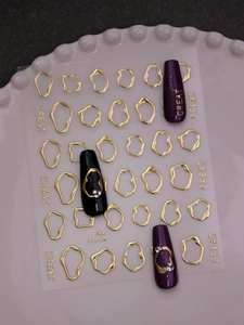 Detailed view of 3D gold geometric loop nail art stickers on long purple manicured nails
