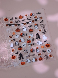 Macro detail of Halloween nail art stickers featuring pumpkins and ghosts on model DEC-026