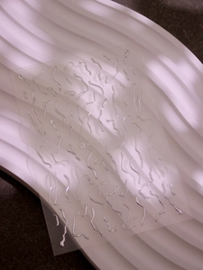 Detailed macro view of 3D metallic silver wavy line nail stickers for manicures