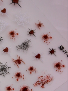 Macro detail of Halloween nail stickers with 3D red blood drops and black spider web patterns