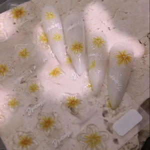 Detailed 5D embossed yellow floral nail stickers with artist fonts on white long nails
