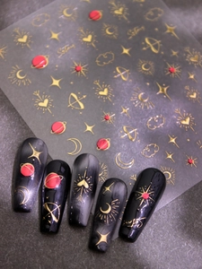 Macro detail of gold celestial nail decals featuring embossed stars and moon designs