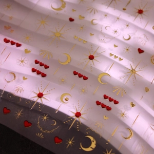 Golden 3D starry moon and red heart nail stickers with metallic gloss on textured background