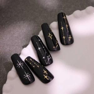 Faux ongles cercueil noir brillant avec des motifs d'étoiles dorées et argentées
