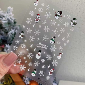 Detail of Christmas nail stickers featuring white snowmen and snowflakes on clear base