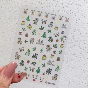 Detail of Christmas nail stickers with reindeer and bell designs on a model's thumb