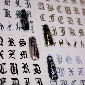 Detail of Gothic alphabet nail stickers with gold and holographic finish on black nails