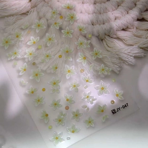 Autocollants 3D pour ongles avec fleurs vertes et blanches et perles sur fond tressé
