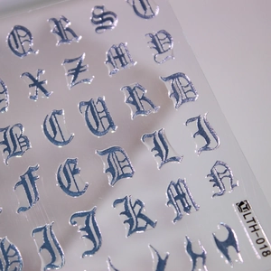 Macro detail of gothic letter nail stickers with metallic silver finish and embossed texture