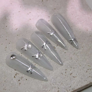 Cat-eye press-on nails with silver metallic bows and rhinestones on stiletto tips