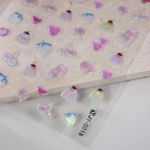 Holographic pink 3D nail art charms with cherry and cupcake shapes on stone background