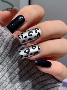 Detail of square nails with glossy black finish and metallic silver leopard print pattern