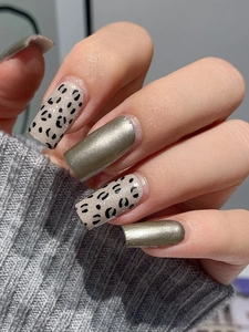 Detailed close-up of square leopard print and olive gold metallic nail stickers on hands