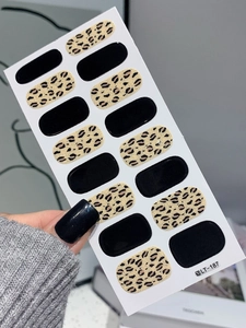 Detail of leopard print and solid black nail wraps on paper backing with model hand