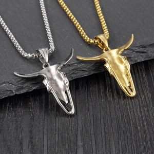 Detail showing western style bull skull pendants in silver and gold on a stone background