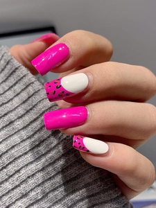 Close-up of pink and leopard print press-on nails on a grey knit sweater background