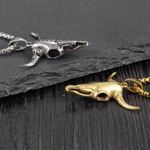 Gothic animal skull necklace in silver and gold steel finish on stone background