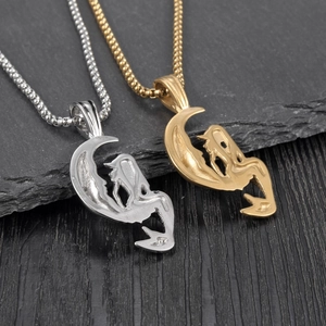 Détails des pendentifs lune et sirène en argent et or sur une surface rocheuse