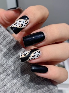Close-up of leopard print nails with black accents and gold glitter details