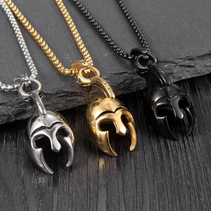 Détail des pendentifs casque spartiate en or, argent et noir sur fond en ardoise sombre