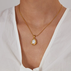 Détail d'un collier pendentif perle vintage porté avec une chemise blanche style rétro