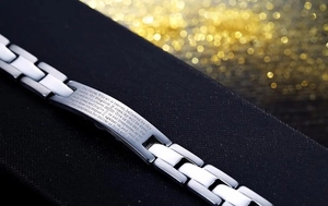 Macro view of Lord's Prayer engraving and cross on polished stainless steel link bracelet