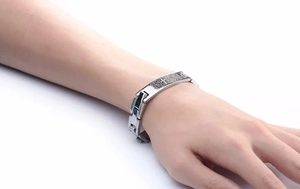 Close-up of stainless steel chain bracelet with engraved religious cross and scripture