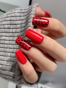 Macro shot of red leopard print and solid red square press-on nails with knit texture