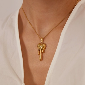 Détail d'un pendentif en forme de cœur fondu doré avec effet métal liquide sur chaîne