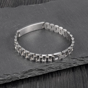 Macro detail of silver titanium steel watchband bracelet on a black stone plate surface