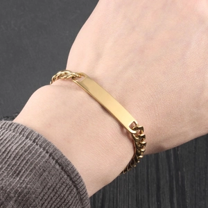 Gros plan d'un bracelet d'identité en acier inoxydable plaqué or porté au poignet