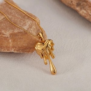 Vue détaillée d'un pendentif cœur en lave dorée sur pierre avec fond à texture douce