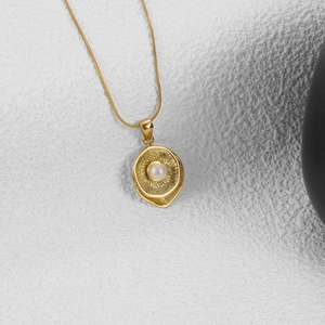 Chic gold snake chain necklace featuring a radiant sunburst pendant with a central pearl
