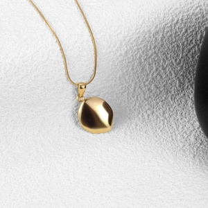 Minimalist gold organic oval pendant necklace on a refined white stone display