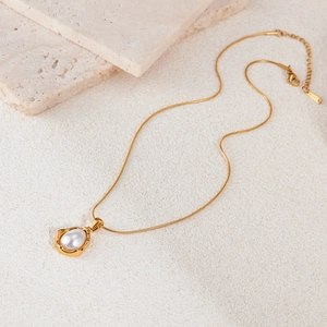 Collier vintage français avec perle et acier inoxydable doré sur une surface en pierre